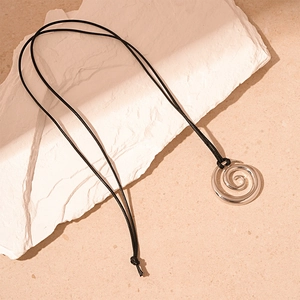 Close-up of silver spiral donut pendant on black braided cord over white stone