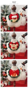 Detailed close-up of handmade crochet Christmas pet bibs with elk and bell patterns