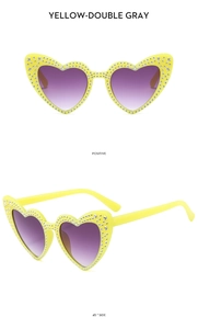 Detailed view of yellow heart-shaped sunglasses with crystal-studded frames and purple lenses