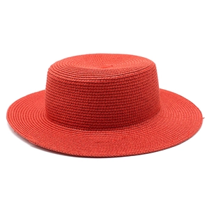 Macro detail of high-quality red woven straw texture on a flat-top summer boater hat