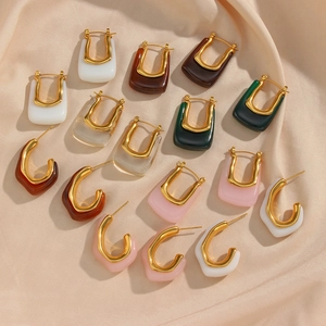 Macro shot of colorful acrylic U-shaped and C-shaped earrings on beige satin fabric