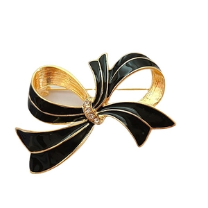 Vintage style golden bow brooch with black enamel and rhinestones on white background