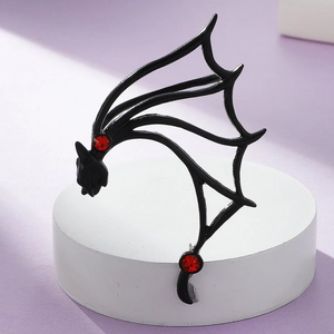 Macro view of gothic matte black bat wing ear cuff with sparkling red rhinestones