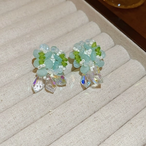 Detail of handcrafted blue flower earrings with crystal teardrop pendants on a velvet tray