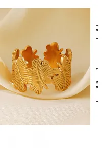 Macro detail of golden stainless steel ring featuring textured leaf motifs and matte finish