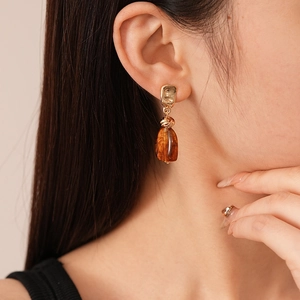 Maillard acrylic irregular geometric amber earrings with golden metal stud on female model