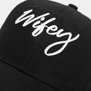 Detailansicht der weißen Wifey-Stickerei auf schwarzem Baumwoll-Twill-Baseballcap