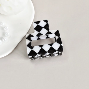 Close-up of black and white checkerboard hair claw clip on a stylish decorative tray