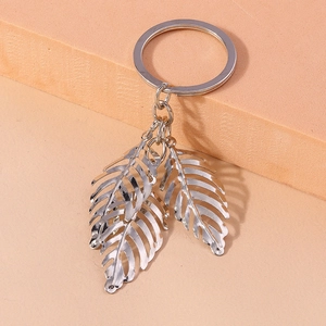 Macro detail of silver alloy hollow feather pendants on a minimalist metal keychain