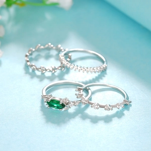 Detalle de set de cuatro anillos de plata con piedra verde y motivo de hojas elegantes