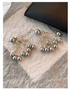 Detail shot of vintage silver tassel earrings with grey pearls on white paper background
