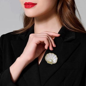 French retro shell brooch with pearl in gold metal frame on black suit lapel