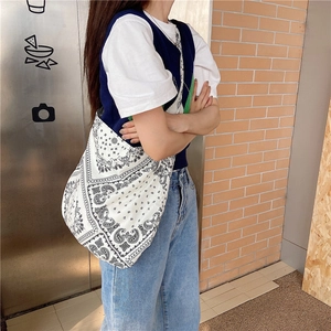 Detailed side view of large canvas tote bag with black and white paisley pattern on shoulder