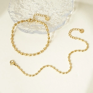 Detail of gold oval bead necklace and bracelet set in polished stainless steel