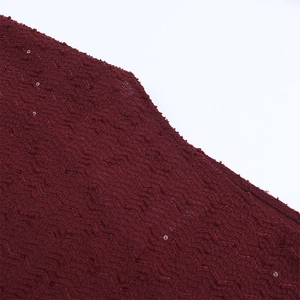 Détail du tissu tricoté rouge foncé pour robe de soirée avec plis ondulés et paillettes