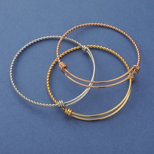 Close-up of twisted stainless steel cable bracelets in silver gold and rose gold finishes