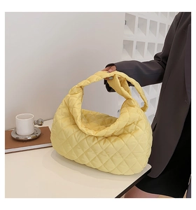 Detailed shot of yellow quilted puffer tote bag featuring soft diamond texture handles
