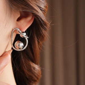 Close-up of a silver metal twisted earring with double spheres worn by a model