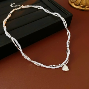 Detail of double-layer pearl and silver chain necklace with heart pendant on display stand