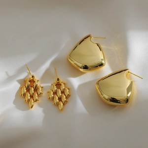 Minimalist geometric gold drop earrings with diamond shapes on white silk background
