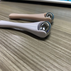 Detail view of two mini alloy eye cream massagers with plastic handles in white and pink