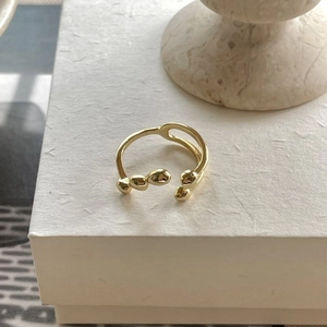 Minimalist irregular gold open ring with an organic streamline design on textured box