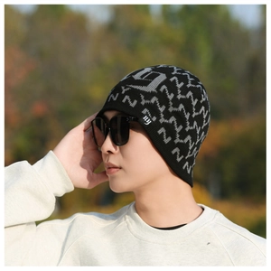 Detail of a black knit beanie with gray N patterns and a small ny label worn outdoors