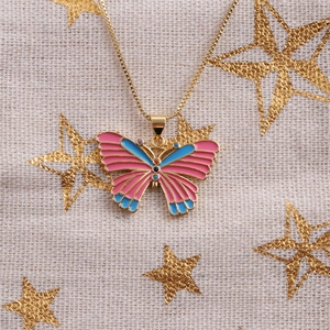 Detail of a gold butterfly necklace with pink and blue enamel wings and colorful stones