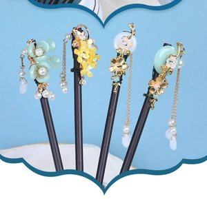 Detailed view of four vintage wooden hair sticks with floral accents and tassels