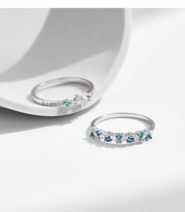 Detail of silver rings featuring mint green and white gemstones in a stacked design