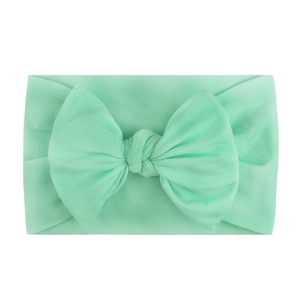 Soft mint green nylon baby headband featuring a large handmade elastic bow
