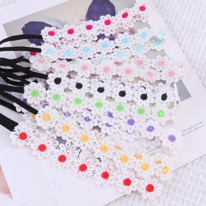 Detailed close-up of colorful embroidered daisy flower elastic headbands for baby girls