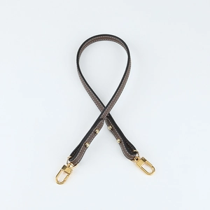 Close-up of lychee grain leather handbag strap with gold hardware and lobster clasps