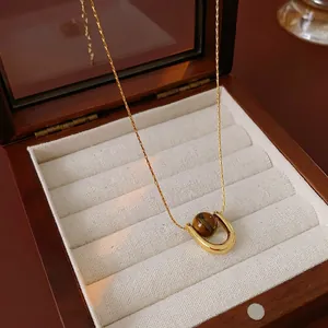 Minimalist titanium steel necklace featuring a gold horseshoe pendant with brown tiger eye stone