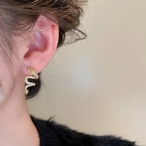 Close-up of a gold dragon earring with zircon stones worn by a model on her ear