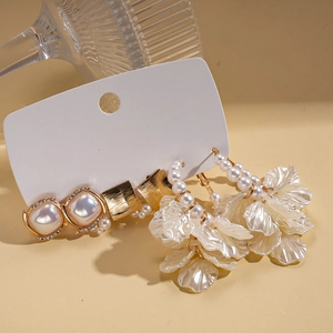 Detail view of pearl and rhinestone earring set featuring square studs and flower tassels