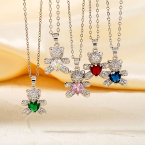 Detail view of heart-shaped gemstones and sparkling teddy bear necklace on silk fabric