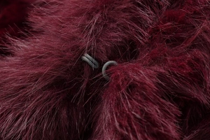 Macro detail of wine red faux fur jacket featuring hidden hook-and-eye closure system