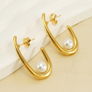 Boucles d'oreilles en U dorées 18 carats avec perles sur fond minimaliste chic