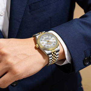 Detailed close-up of luxury gold and silver dual-tone calendar quartz watch on male wrist