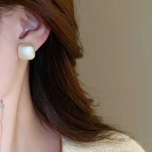 Macro shot of minimalist matte square pearl earring worn by model for elegant style