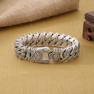 Close-up of vintage silver curb chain bracelet with intricate ethnic pattern engraving