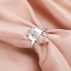 Minimalist silver cat-shaped stainless steel ring displayed on soft pink silk fabric