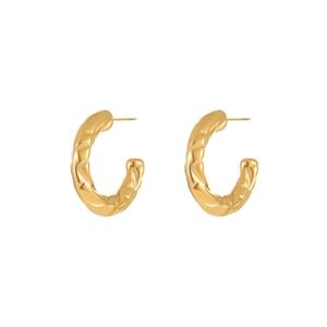Detailed macro view of gold C-shaped hoop earrings featuring a luxury quilted texture