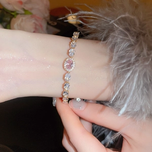 Detail of elegant gold bracelet with pink zirconia stones on a model's wrist