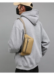Detail view of khaki multi-compartment waist bag on model showing adjustable strap
