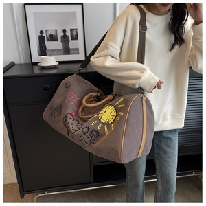 Detail of large canvas travel bag with playful graffiti prints and leather straps