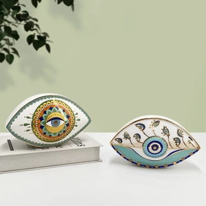 Detail of ceramic evil eye ornaments with mandala patterns and gold accents on a white table