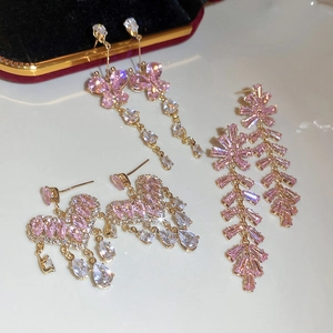 Detail shot of golden heart and butterfly tassel earrings with sparkling pink zircons