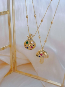 Detail of gold-plated mushroom and ladybug necklaces with vibrant colorful zircons